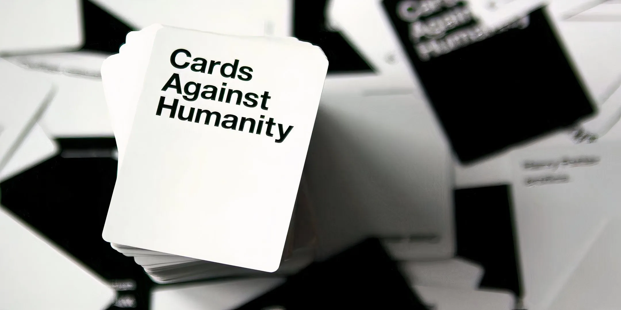Bộ bài Cards Against Humanity màu đen trắng trên bàn, biểu tượng của một thời kỳ game party bùng nổ.