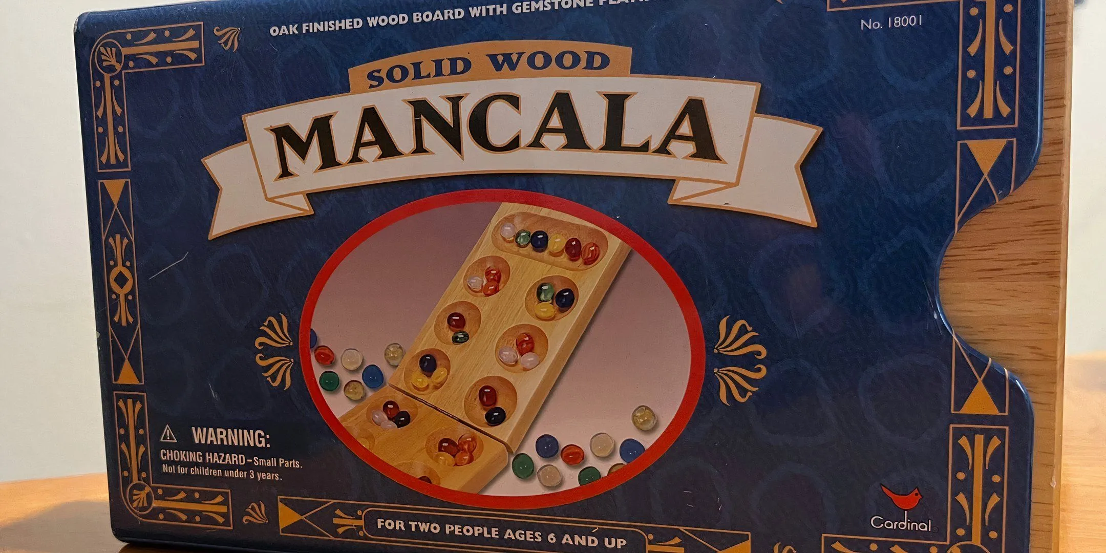 Hộp game Mancala, trò chơi chiến thuật cổ điển với những viên bi đầy màu sắc và luật chơi đơn giản.